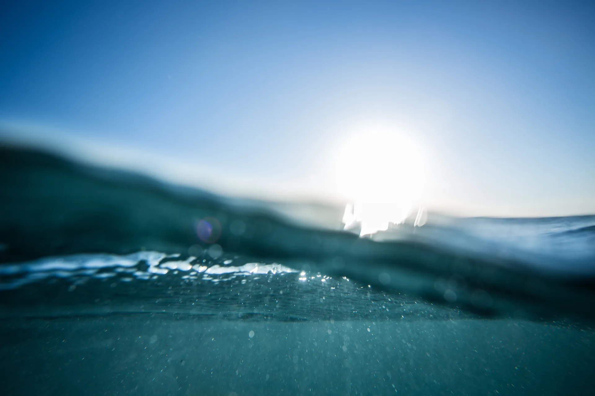 Sunlight on ocean waves at the waterline, viewed from above and below the surface